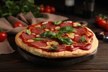 Pita pizza with pepperoni, cheese and basil on wooden table, closeup