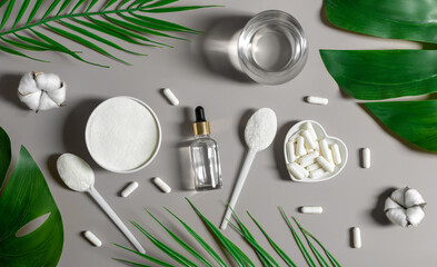 Set of collagen on a gray background with leaves. Collagen powder, capsules and liquid collagen. Natural supplement for skin beauty and bone health. View from above.