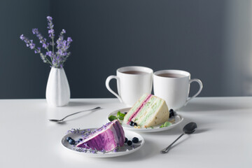berry cheesecakes and two cups of tea on  white table on background gray wall