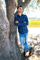 Man dressed up leaning against a tree