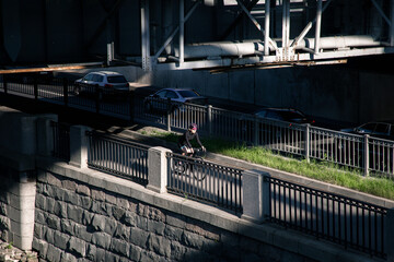 Obraz premium View of the cyclist illuminated by the sun in the morning in the city on the embankment. Cycling around the city. Training preparation for the competition.