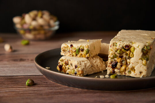 Organic halva with pistachios on a wooden surface. Traditional middle eastern sweets. Jewish, turkish, arabic oriental national dessert. Turkish delight concept. Natural vegan product. Copy space.