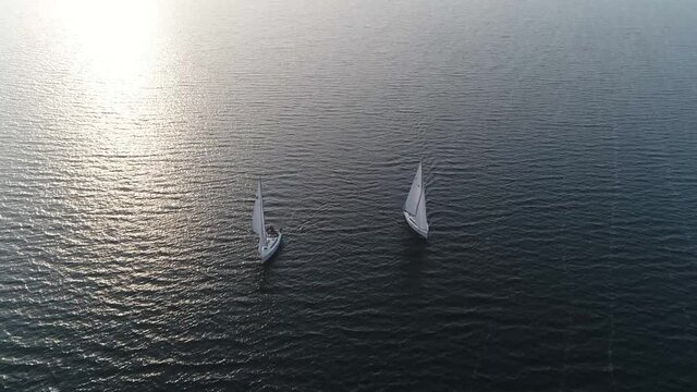 High altitude aerial view of two sloops on quiet and lonely ocean the type is sailboat with a single mast typically having only one headsail in front of it and another mainsail aft 4k quality