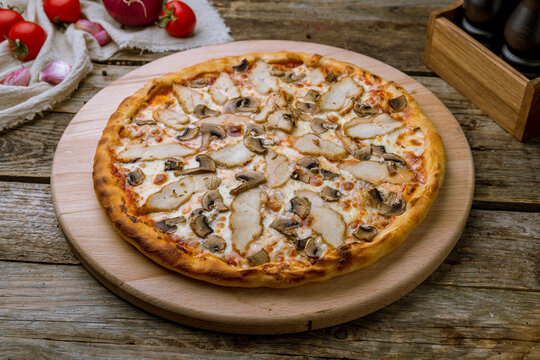 Pizza with chicken and mushrooms on old wooden table