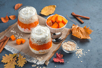 Creamy parfait with pumpkin and cereals on a dark blue background. Side view, space for copying. Vegetarian dessert.