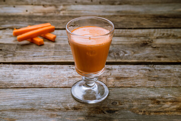 Fresh carrot in a glass with creamy on a wooden background