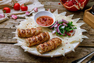 Lula kebab chicken with onions and tomato sause on old wooden table