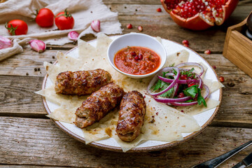 Lamb Lula kebab with sliced onions and tomato sause on old wooden table