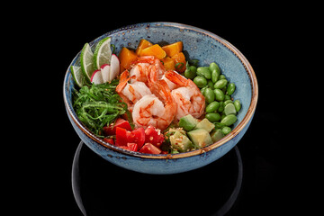 Poke bowl with shrimps, mango, tomatoes, avocados, edamame beans, rice, wakame seaweed, radish and lime
