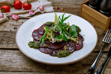 beetroot carpaccio with sause pesto on plate on old wooden table - 446682506