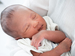 Portrait of two weeks African American newborn baby or infant lying on the white bed and open his eyes...