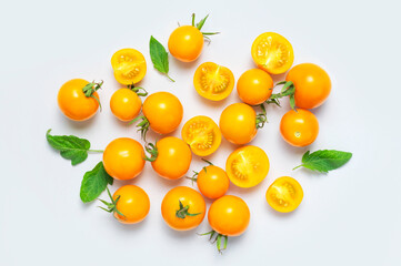 Ripe fresh yellow orange tomatoes with green tails, leaves on light gray background flat lay top view. Cherry tomatoes. Vegetables, healthy vegan organic food, harvest concept tomatoes layout cooking