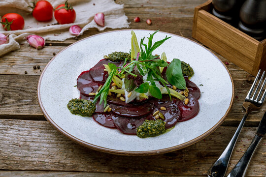 beetroot carpaccio with sause pesto on plate on old wooden table
