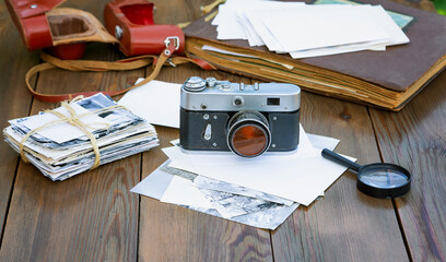 Film camera and old photographs. A bundle of old photographs, photo album on a wooden table.