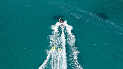 Aerial photo of extreme power boat donut water-sports cruising in high speed in tropical emerald bay