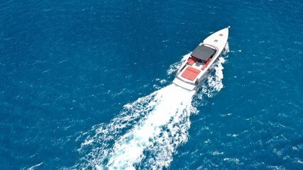 Obraz premium Aerial drone photo of small luxury speed boat cruising in deep blue waters of Mykonos island, Cyclades, Greece