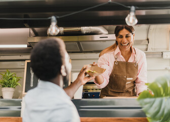 Happy Hispanic seller giving takeaway salad to black client