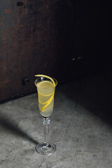 french 75 champagne cocktail with lemon twist garnish in flute glass against rustic concrete metal 