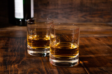 Glasses of strong scotch single malt whisky served on dark wooden table in old pub