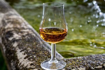 Glass of strong scotch single malt whisky served on old stone reservoir for water from mountain spring