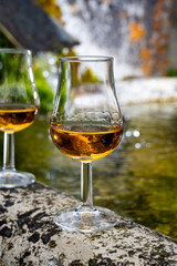 Glasses of strong scotch single malt whisky served on old stone reservoir for water from mountain spring