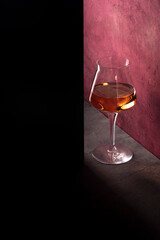 glass of pink wine on lilac background concept dramatic art with shadows