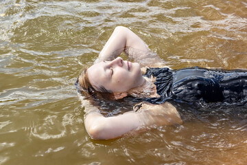 Portrait of a young woman close-up in the water. Swimming in the lake