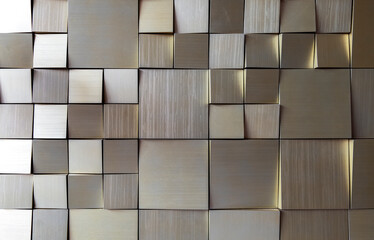 small square gold tiles on the wall. rough surface texture