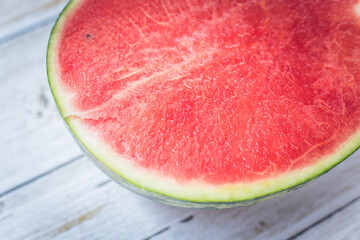 The watermelon is ripe, seedless, cut in half, on a light-colored wooden floor.