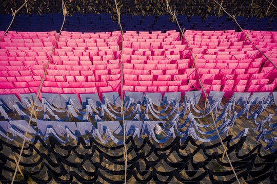 Aerial view of workers hanging thousands of meters of different coloured t-shirt fabrics to dry in Narayanganj, Dhaka, Bangladesh.