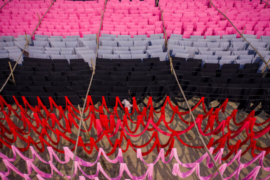Aerial view of workers hanging thousands of meters of different coloured t-shirt fabrics to dry in Narayanganj, Dhaka, Bangladesh.