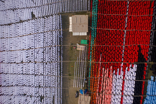 Aerial view of workers hanging thousands of meters of different coloured t-shirt fabrics to dry in Narayanganj, Dhaka, Bangladesh.