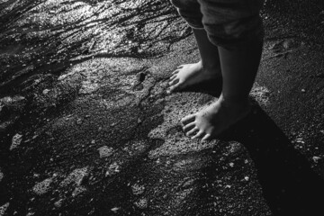Little girl feet in the sand in front of the sea (in black and white)