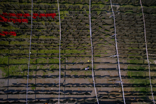 Aerial view of workers hanging thousands of meters of different coloured t-shirt fabrics to dry in Narayanganj, Dhaka, Bangladesh.