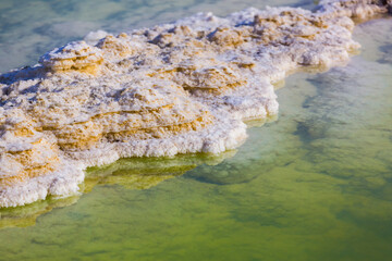 Salt seashore in Israel, Dead Sea. Salt crystals and formations in blue water. White crystals close up