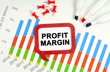 There are markers, charts and a sign on the table - PROFIT MARGIN