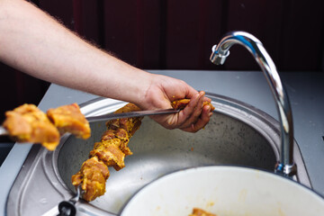 The chef stringing meat on skewers for cooking