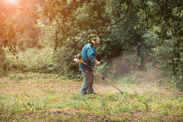 a worker mows the grass with a trimmer