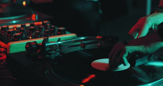 Deejay playing music, black vinyl record spinning on DJ turntable during party performance. Nightlife concept