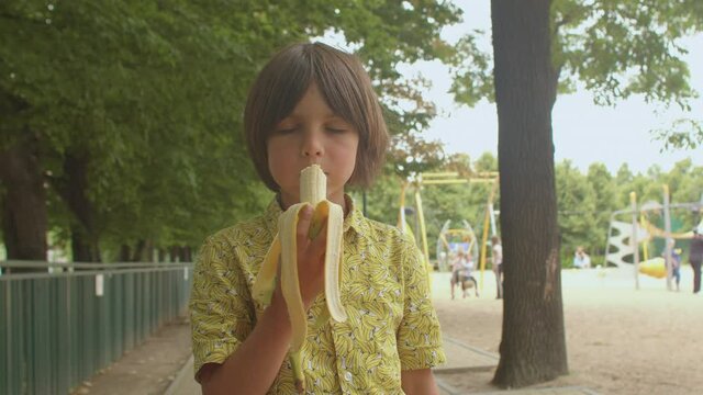 A boy in a yellow shirt is eating a banana. Foods that affect the hormones, plant products stimulate the production of endorphins. The hormone of happiness.
