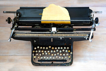 An old Soviet typewriter with keys with Russian letters and a sheet of yellow paper