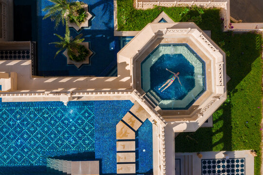 Aerial view of a woman relaxing in a swimming pool in a luxury hotel in India.