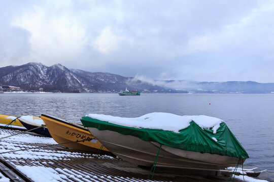 Boat dock on the covered by snow during winter season with beautiful landscape view of Lake Toya in Shikotsu-Toya National Park, Hokkaido, Japan.