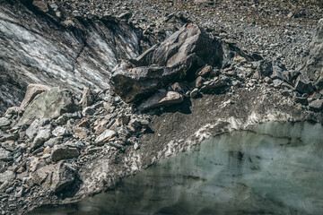 Nature background with icefall near glacier with cracks and scratches. Natural backdrop with icy wall and moraines. Beautiful landscape with shiny glacial wall and stones in sunlight. Glacier texture.