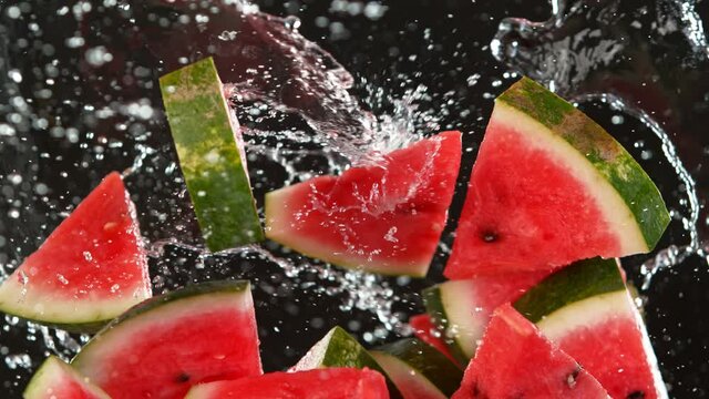 Super Slow Motion Shot of Flying Fresh Melon Cuts and Water Side Splash Isolated on Black at 1000 fps.