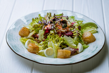Salad with crab and scallop on white wooden table