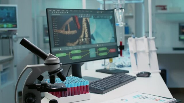 Empty laboratory with dna animation on computer and chemical equipment. Nobody in science room with documents, microscope, test tubes, micropipette and vacutainer for experiment