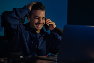 Young Colombian Latino talks on his cell phone while working at home