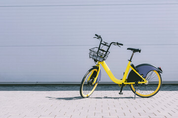 Rent a bike, a yellow bike stands against a gray wall.