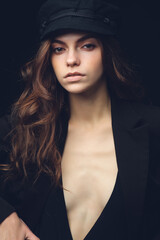 Girl on a black background. Low key. Nice young girl in a hat on a black studio background.